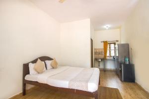 a bedroom with a bed with white walls and wooden floors at Calangute Bay By The Sea in Calangute