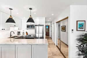 a kitchen with white cabinets and a large island at Noelani 104 in Kahana