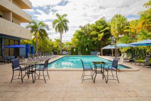 - une piscine avec des tables et des chaises à côté d'un complexe dans l'établissement Regency Miami Airport by Sonesta, à Miami