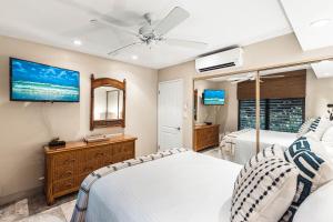 a bedroom with two beds and a flat screen tv at Noelani 104 in Kahana