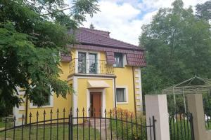 une maison jaune avec une clôture devant elle dans l'établissement Okouzlující vila u jezera Lhota, à Lhota