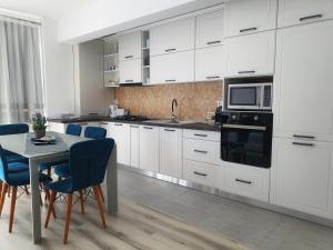 a kitchen with white cabinets and a table with blue chairs at Minas Dream in Floreşti