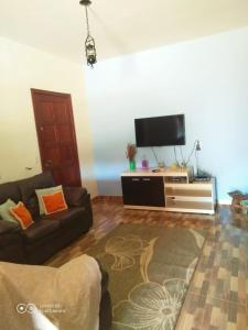 a living room with a couch and a flat screen tv at Casa da Seriema em Lapinha da Serra in Santana do Riacho