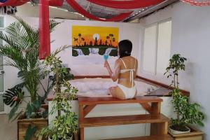 una mujer sentada en un banco en una habitación con una pintura en Villa Isai.Hospedaje Spa.., en Baños