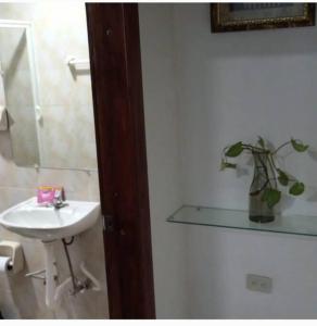 Baño blanco con lavabo y espejo en Villa Isai.Hospedaje Spa.., en Baños