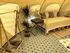 a tent with a bed and a table in it at Tallulah Belle in Abbots Bromley