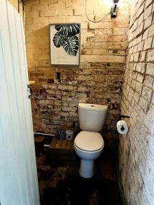 uma casa de banho com um WC branco numa parede de tijolos em Tallulah Belle em Abbots Bromley