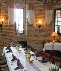 a dining room with white tables and chairs and windows at Am Wasserturm Pension in Bad Muskau