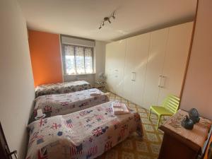 um quarto com 2 camas e uma cadeira verde em SANT'ANNA SWEET HOME AI CONFINI DELLE LANGHE em Narzole