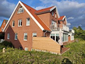 ein großes Backsteinhaus mit einer Terrasse auf einem Hügel in der Unterkunft Ferienwohnung Bootsmann in Langeoog