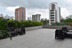 um pátio no último piso com cadeiras, mesas e edifícios em Apartaestudio DISTRITO 90 em Barranquilla