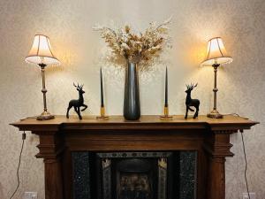 Abbotsford Guest House في إدنبرة: موقد عليه شمعتين و مزهرية عليها تماثيل غزلان