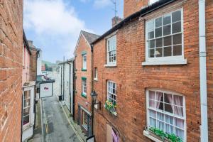 an alley with brick buildings and flowers in windows at Ludlow Escapes - Ludlow Town Centre Apartments in Ludlow