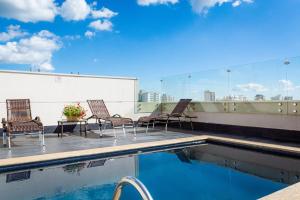 a group of chairs sitting on a rooftop with a pool at Blue Tree Towers Bauru in Bauru