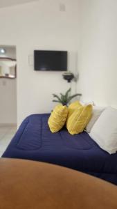 Una cama con cuatro almohadas amarillas. en Departamento Aristobulo en La Cieneguita