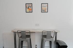 a table with two stools and two pictures on the wall at Bentley Lofts - By Sigma Stays in Crewe