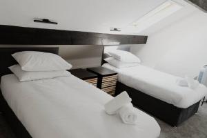 two beds in a room with white sheets and pillows at Bentley Lofts - By Sigma Stays in Crewe