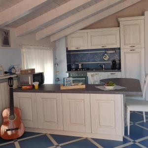 ラ・スペツィアにあるCasa Bouganvilleの白いキャビネットとギター付きのキッチン
