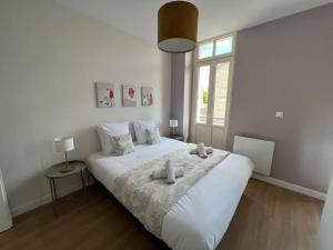 een slaapkamer met een groot wit bed met twee knuffels erop bij Appartement centre ville * terrasse * clim * WIFI * Haut de gamme * in Angoulême