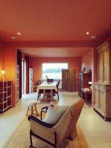 un soggiorno con pareti arancioni, tavolo e sedie di Roos 14, sfeervol vakantieverblijf in hartje Hageland a Kortenaken