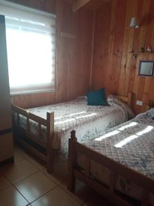 a bedroom with two beds and a window at Cabaña Beatriz in Coñaripe