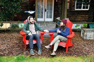 two people sitting in red chairs in front of a house at Anchor Inn Resort in Lincoln City