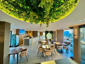 a restaurant with tables and chairs under a ceiling with plants at Nobbu Hotel Ksamil in Ksamil