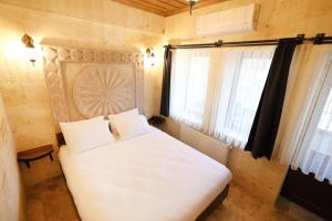 a bedroom with a large white bed and a window at Rocca Stone House in Goreme