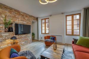 uma sala de estar com mobiliário laranja e uma parede de tijolos em Le Baroque clim et sauna em Annecy