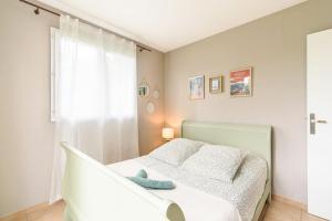 a white bedroom with a bed and a window at New Charmante maison proche océan in Biscarrosse