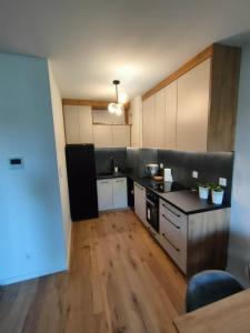a kitchen with black counter tops and wooden floors at Apartament Leśna Mandala in Augustów