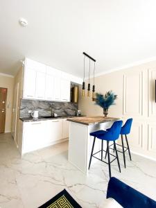 a kitchen with white cabinets and blue bar stools at Glamor Lux in Gdańsk