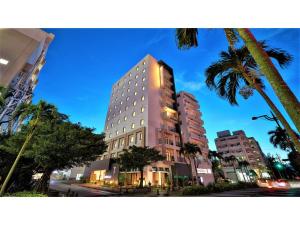un edificio alto en una calle de la ciudad con palmeras en Y's Inn Naha Oroku Ekimae - Vacation STAY 25852v, en Naha