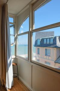 a room with three windows with a view of the ocean at Villa Adèle, vue mer, sauna et plage in Mers-les-Bains