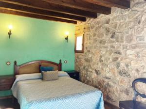 1 dormitorio con cama y pared de piedra en Acebos del Tajo, en Peralejos de las Truchas