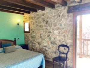 sypialnia z łóżkiem i kamienną ścianą w obiekcie Acebos del Tajo w mieście Peralejos de las Truchas