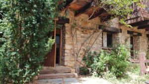 une ancienne maison en pierre avec une porte en bois et une échelle dans l'établissement Acebos del Tajo, à Peralejos de las Truchas