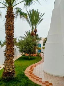 a walkway with palm trees in a resort at VILLA "Mezraya" à 500 m de la plage - DJERBA in Mezraya