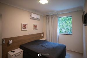 een hotelkamer met een bed en een raam bij Flat com Piscina Térmica no Bombinhas Summer Beach in Bombinhas