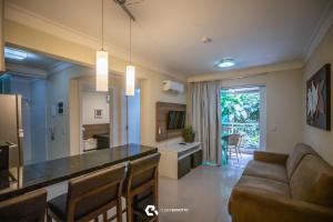 a kitchen and living room with a bar and a couch at Flat com Piscina Térmica no Bombinhas Summer Beach in Bombinhas