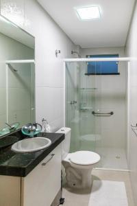 a bathroom with a toilet and a glass shower at Flat com Piscina Térmica no Bombinhas Summer Beach in Bombinhas