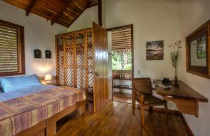 a bedroom with a bed and a desk and a table at Villa Toucan with National Geographic Views in Puerto Viejo