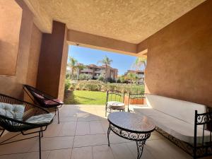 a porch with a couch and chairs and a table at Corail Apart Golfique -Prestigia in Marrakech
