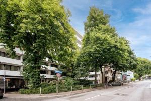 una calle con árboles frente a un edificio en HH 02 Modernes Apartment am Winterhuder Marktplatz, en Hamburgo