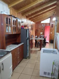 cocina con armarios de madera y nevera negra en Cabaña Beatriz, en Coñaripe