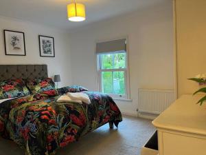 Un dormitorio con una cama con una manta de flores y una ventana en Chic 2 bedroom cottage en Willingham