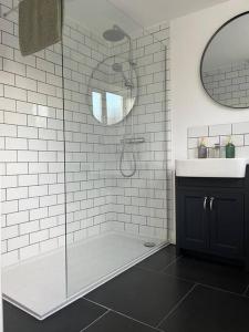 a bathroom with a shower with a sink and a mirror at Chic 2 bedroom cottage in Willingham
