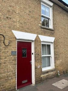 een bakstenen gebouw met een rode deur en een raam bij Chic 2 bedroom cottage in Willingham