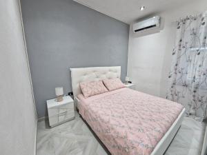a small bedroom with a pink bed with a pink blanket at La Maddalena Holiday Home in La Maddalena