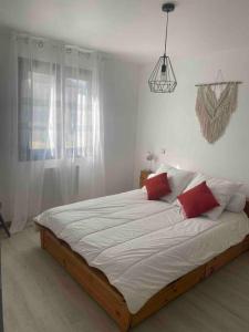 ein Schlafzimmer mit einem großen weißen Bett mit roten Kissen in der Unterkunft Le Val des Prats proche de Rocamadour in Puybrun